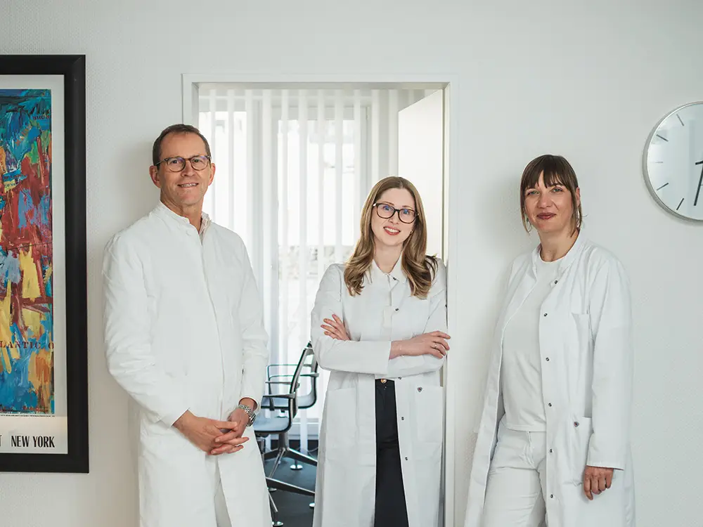 Dr. Schulte-Goebel, dr. Kleophas und Fr. Hage stehen an der Tür zu einem Praxiszimmer